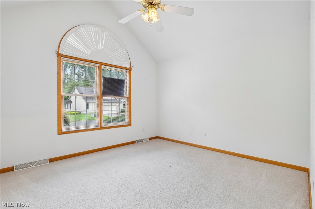 7007 Clingan Road, Unit 85 Youngstown, OH 44514 - Photo 26 of 46 Vaulted ceiling with a ceiling fan, arched window with wood-finish trim, and light-toned carpeting