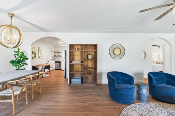 a living room with furniture a mirror and wooden floor