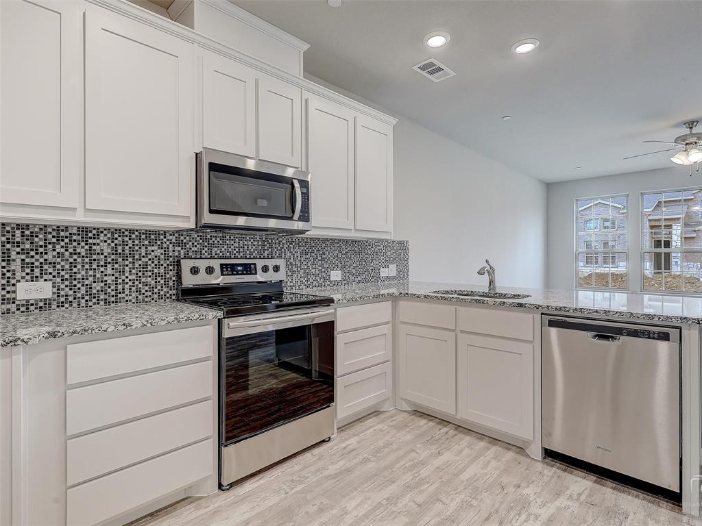 3337 Solana Circle Denton, TX 76207 - Photo 11 of 22 Kitchen with appliances with stainless steel finishes, a ceiling fan, white cabinetry, decorative backsplash, and light stone counters