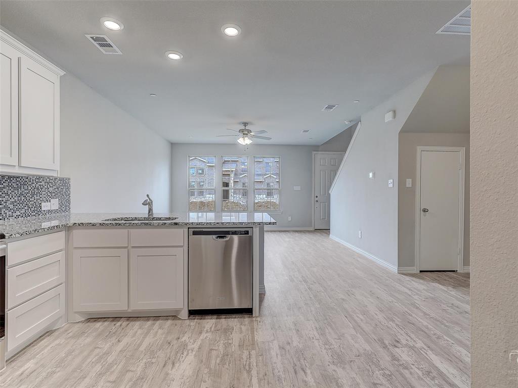 3337 Solana Circle Denton, TX 76207 - Photo 12 of 22 Kitchen with stainless steel dishwasher, ceiling fan, light wood-type flooring, light stone counters, and white cabinetry