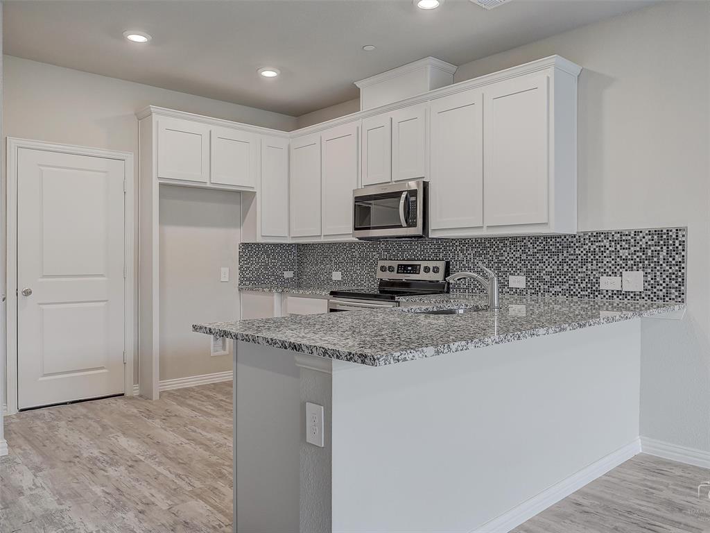 3337 Solana Circle Denton, TX 76207 - Photo 10 of 22 Kitchen with appliances with stainless steel finishes, light stone countertops, a peninsula, white cabinets, and recessed lighting