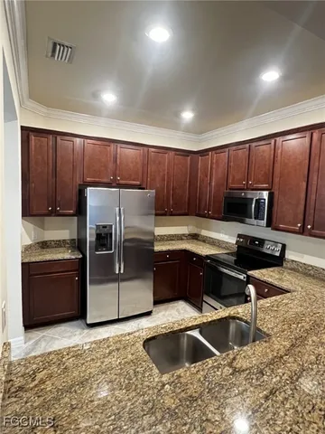 a kitchen with kitchen island granite countertop a sink a stove and refrigerator
