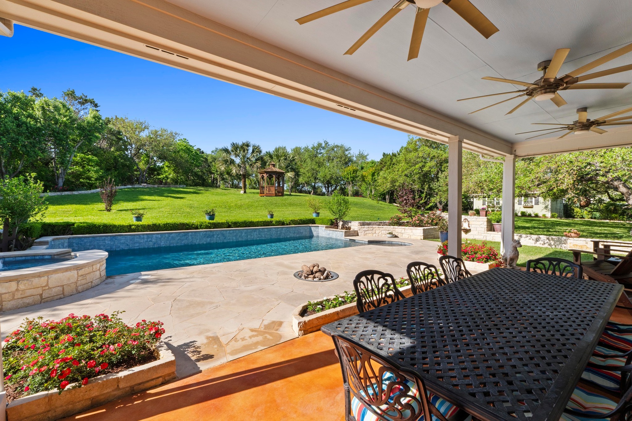 135 Tumbleweed Trail North Austin, TX 78733 - Photo 21 of 39 View of patio/terrace featuring a ceiling fans, outdoor dining area, a pool with a connected hot tub, and a view of trees and the gazebo.