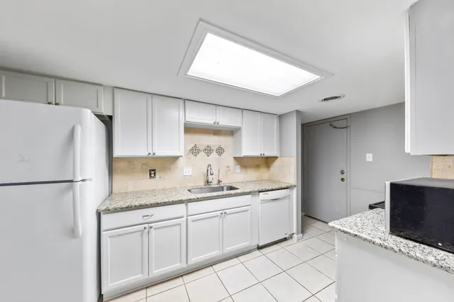 a kitchen with granite countertop white cabinets and white appliances