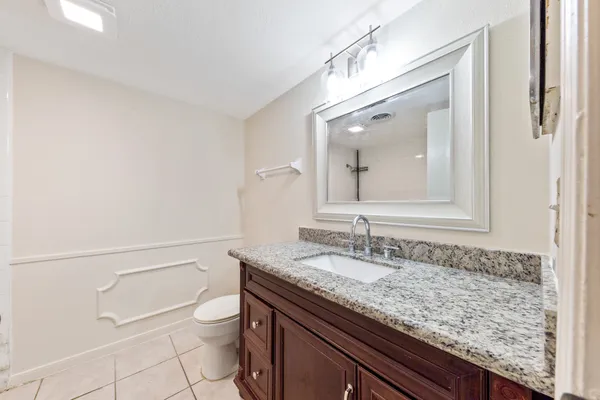 a bathroom with a granite countertop sink a toilet and a mirror