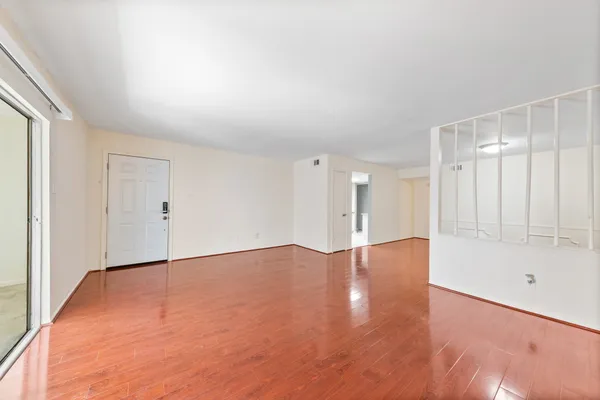a view of an empty room with wooden floor and a window