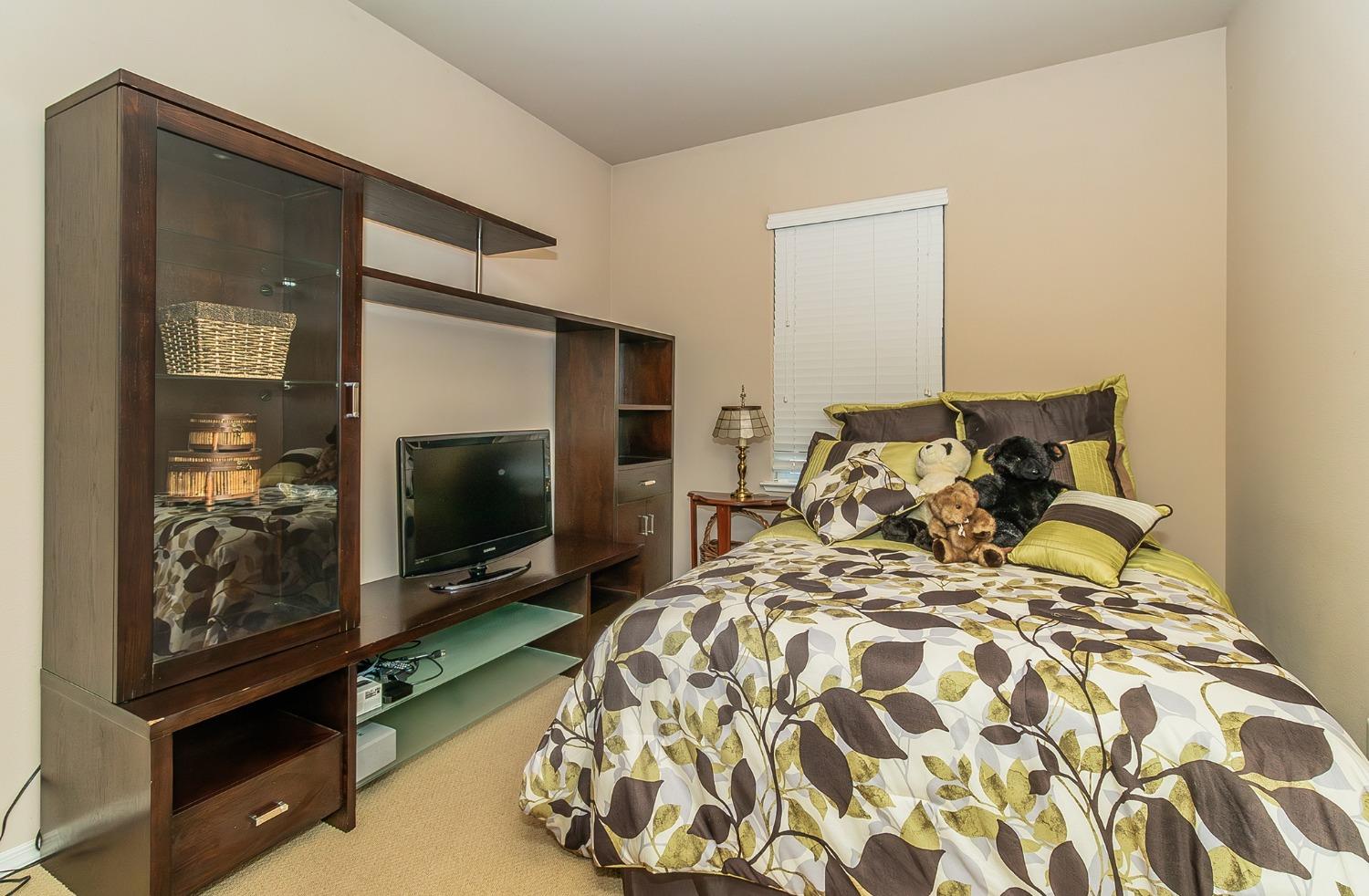 4179 Harlan Ranch Boulevard Clovis, CA 93619 - Photo 22 of 47 a bed sitting in a bedroom next to a flat screen tv