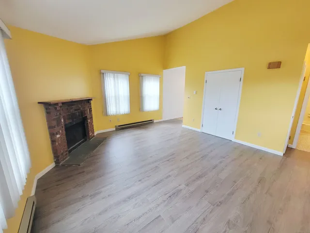 a view of a livingroom with wooden floor and a fireplace
