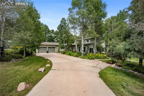 a front view of a house with a garden and trees