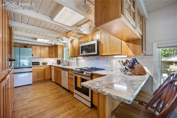 a kitchen with stainless steel appliances granite countertop wooden cabinets a stove top oven a sink and dishwasher