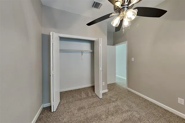 an empty room with closet and a chandelier fan
