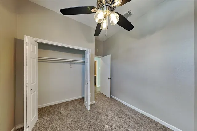 an empty room with closet and a chandelier fan
