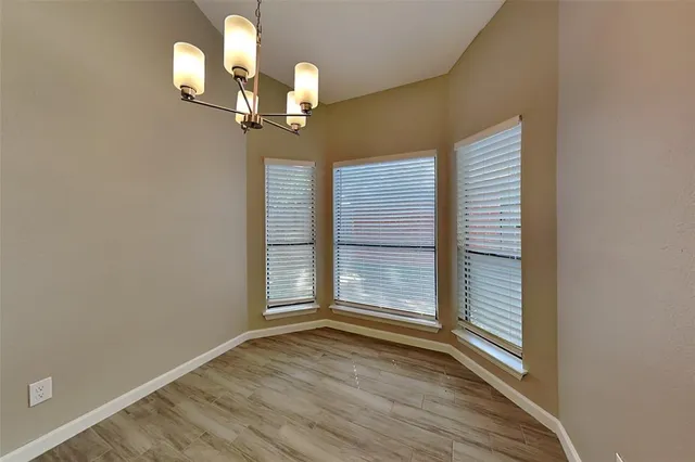 an empty room with wooden floor cabinet and windows