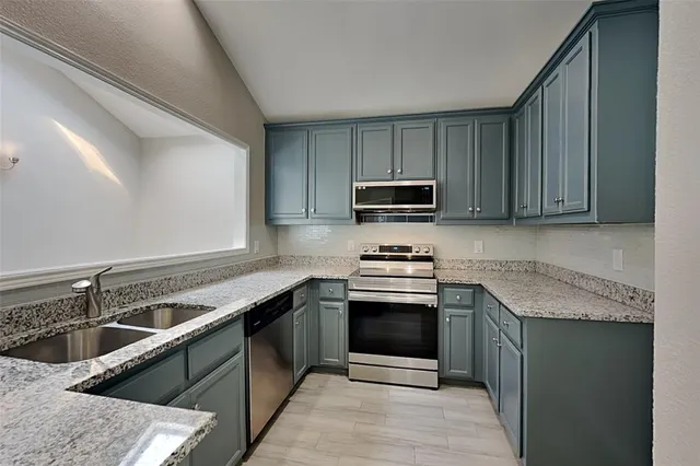 a kitchen with stainless steel appliances granite countertop a sink stove and microwave