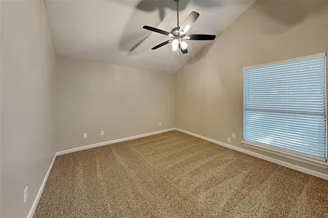an empty room with a ceiling fan and window
