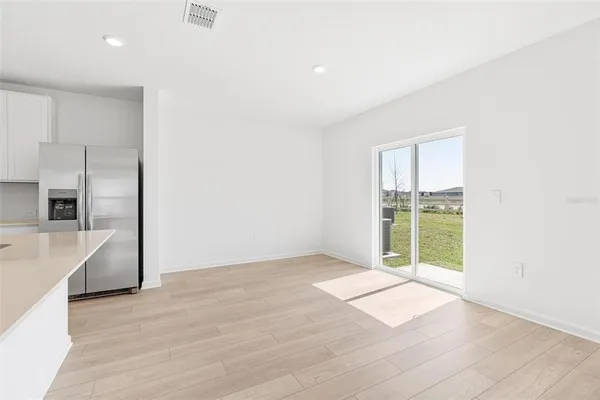 a view of an empty room with a window and kitchen area
