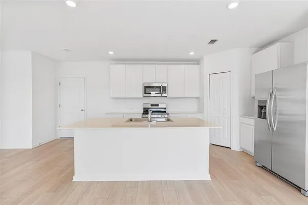 a view of a kitchen with kitchen island a sink a stove and refrigerator