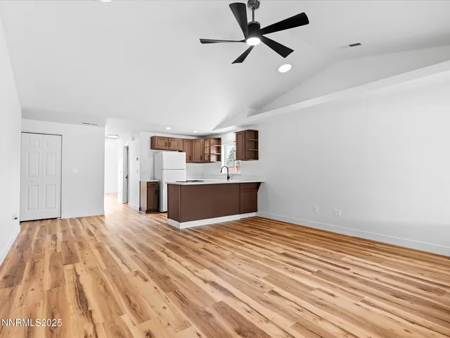 a view of kitchen and empty room with wooden floor