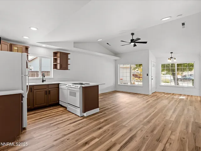 a large kitchen with stainless steel appliances granite countertop a stove a sink dishwasher and a refrigerator with wooden floor