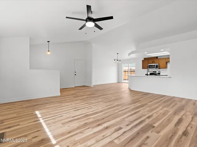 a view of empty room with wooden floor and ceiling fan