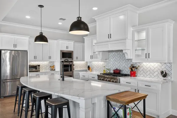 a kitchen with stainless steel appliances granite countertop a sink a stove and chairs