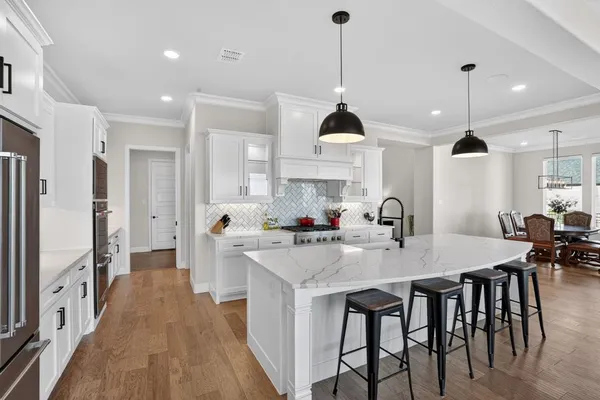 a kitchen with stainless steel appliances kitchen island granite countertop a stove a sink a refrigerator a center island with a dining table and chairs