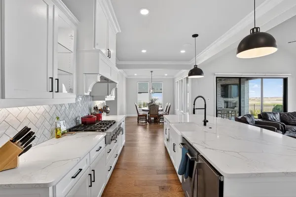 a kitchen with stainless steel appliances a stove a sink a oven a dining table and chairs