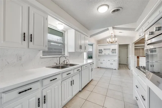 a large white kitchen with a sink and cabinets