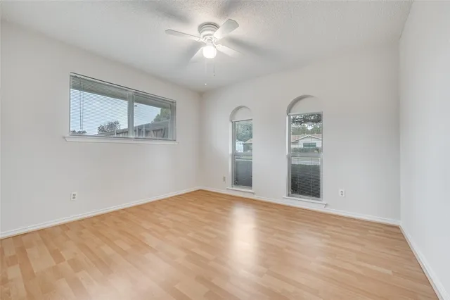 a view of an empty room with window and wooden floor