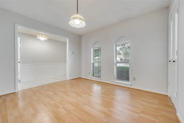 an empty room with wooden floor mirror and windows