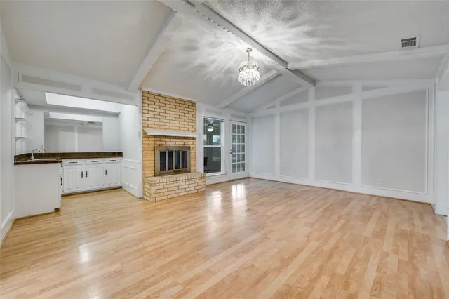 wooden floor in an empty room with a fireplace and a window