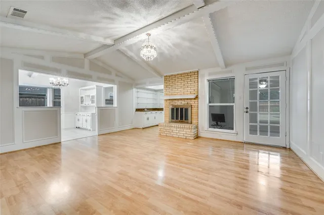 an empty room with wooden floor and a kitchen