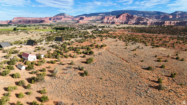 358 South Sky Drive Torrey, UT 84775 - Photo 46 of 82 Expansive desert landscape featuring multiple structures, including A-frame homes and a red-roofed building, surrounded by scattered green foliage