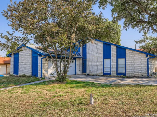 a view of a house with large windows and a tree