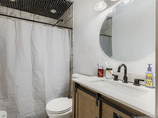 a bathroom with a sink a toilet and shower curtain