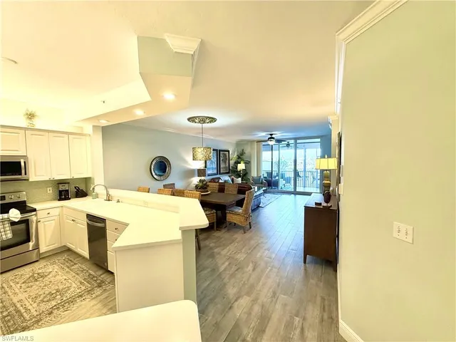 a living room with couches a flat screen tv and kitchen view