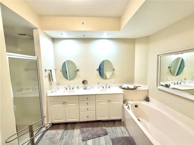 a bathroom with a double vanity sink mirror bathtub and shower