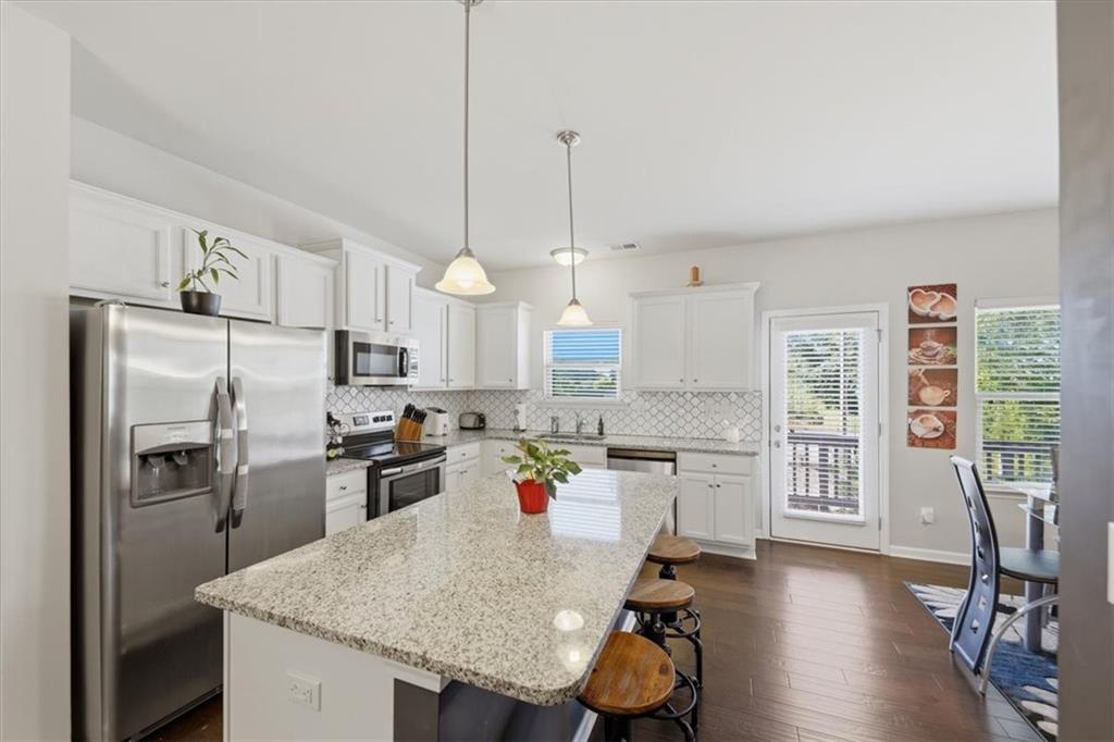 4154 Integrity Way Powder Springs, GA 30127 - Photo 11 of 52 a open kitchen with stainless steel appliances granite countertop a sink dishwasher a refrigerator a stove a dining table and chairs with wooden floor