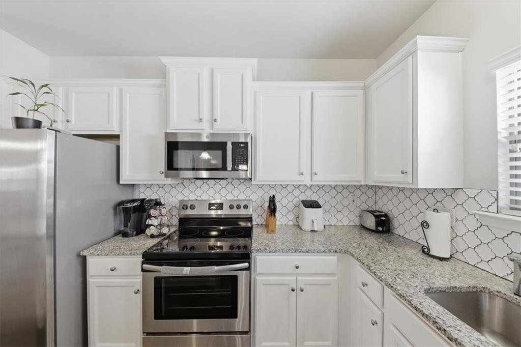4154 Integrity Way Powder Springs, GA 30127 - Photo 14 of 52 a kitchen with granite countertop white cabinets and stainless steel appliances