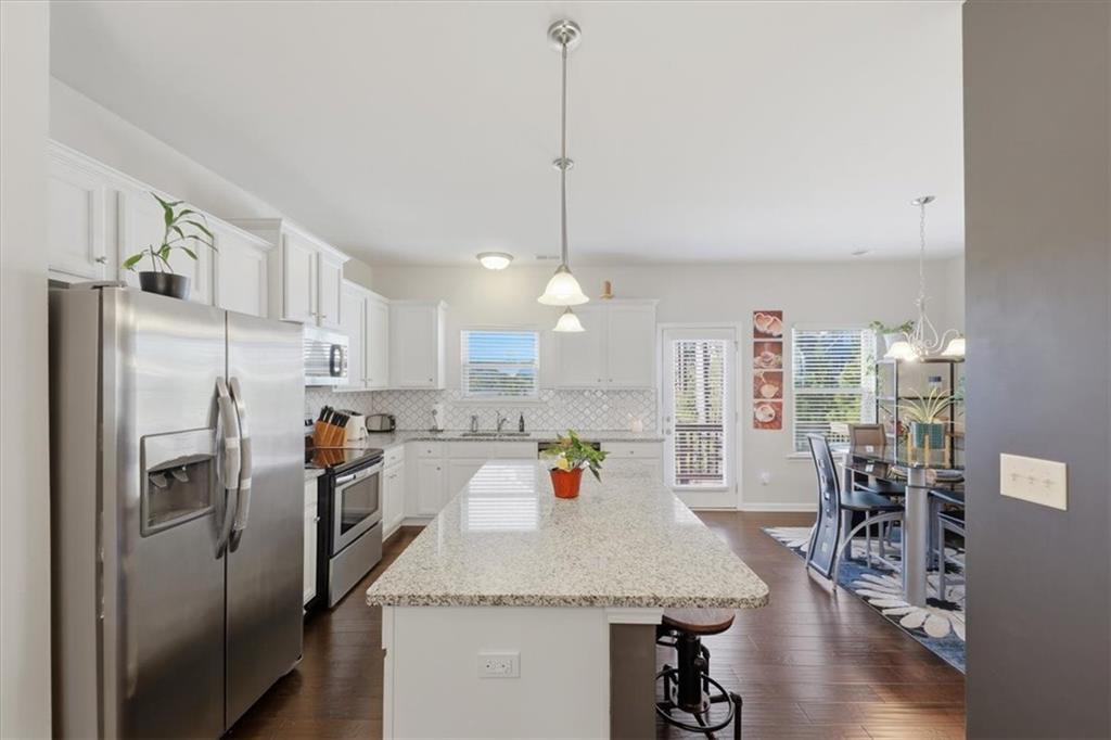 4154 Integrity Way Powder Springs, GA 30127 - Photo 10 of 52 a kitchen with stainless steel appliances granite countertop a refrigerator a sink dishwasher a oven a dining table and chairs with wooden floor