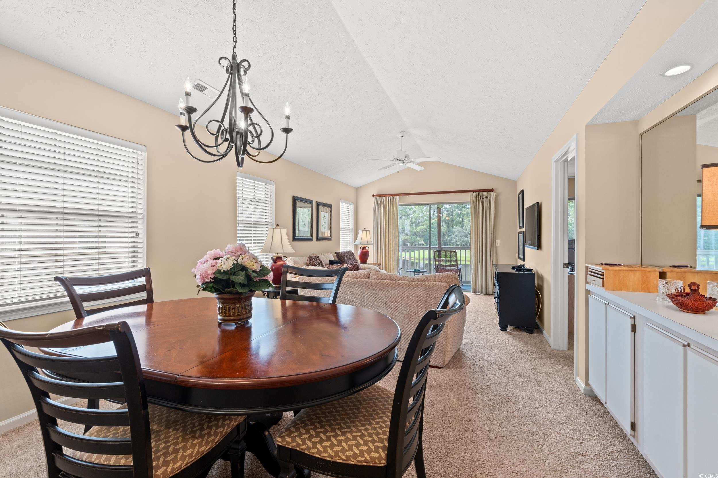 117 Pinehurst Lane, Unit 5E Pawleys Island, SC 29585 - Photo 8 of 40 Dining space featuring vaulted ceiling, light colored carpet, a ceiling fan, and a chandelier