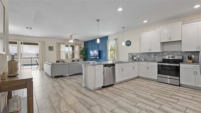 a large white kitchen with cabinets a sink and appliances