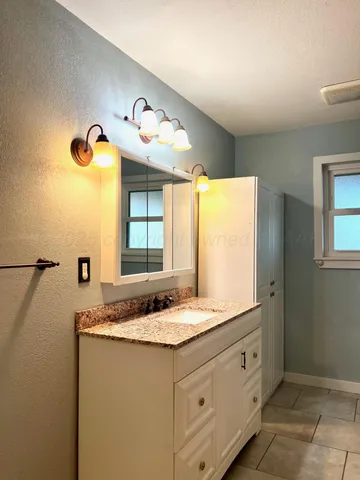 a bathroom with a granite countertop sink and a mirror