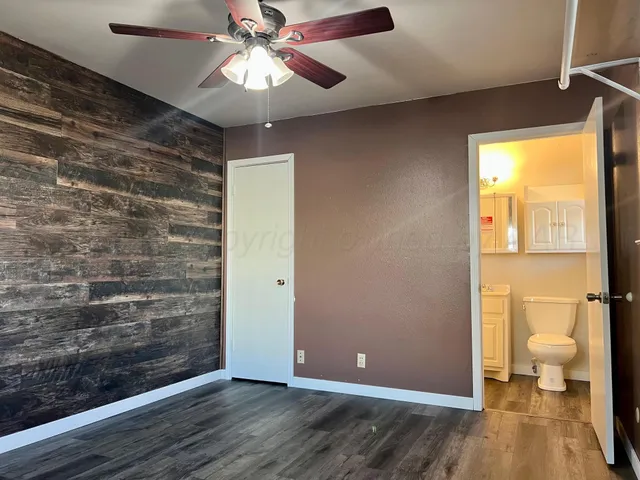 a view of a hallway with wooden floor and a bathroom
