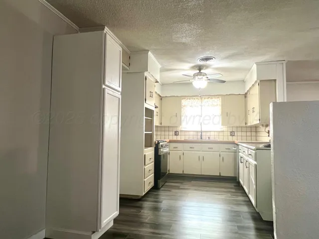 a kitchen with a refrigerator a sink dishwasher a stove and white cabinets with wooden floor