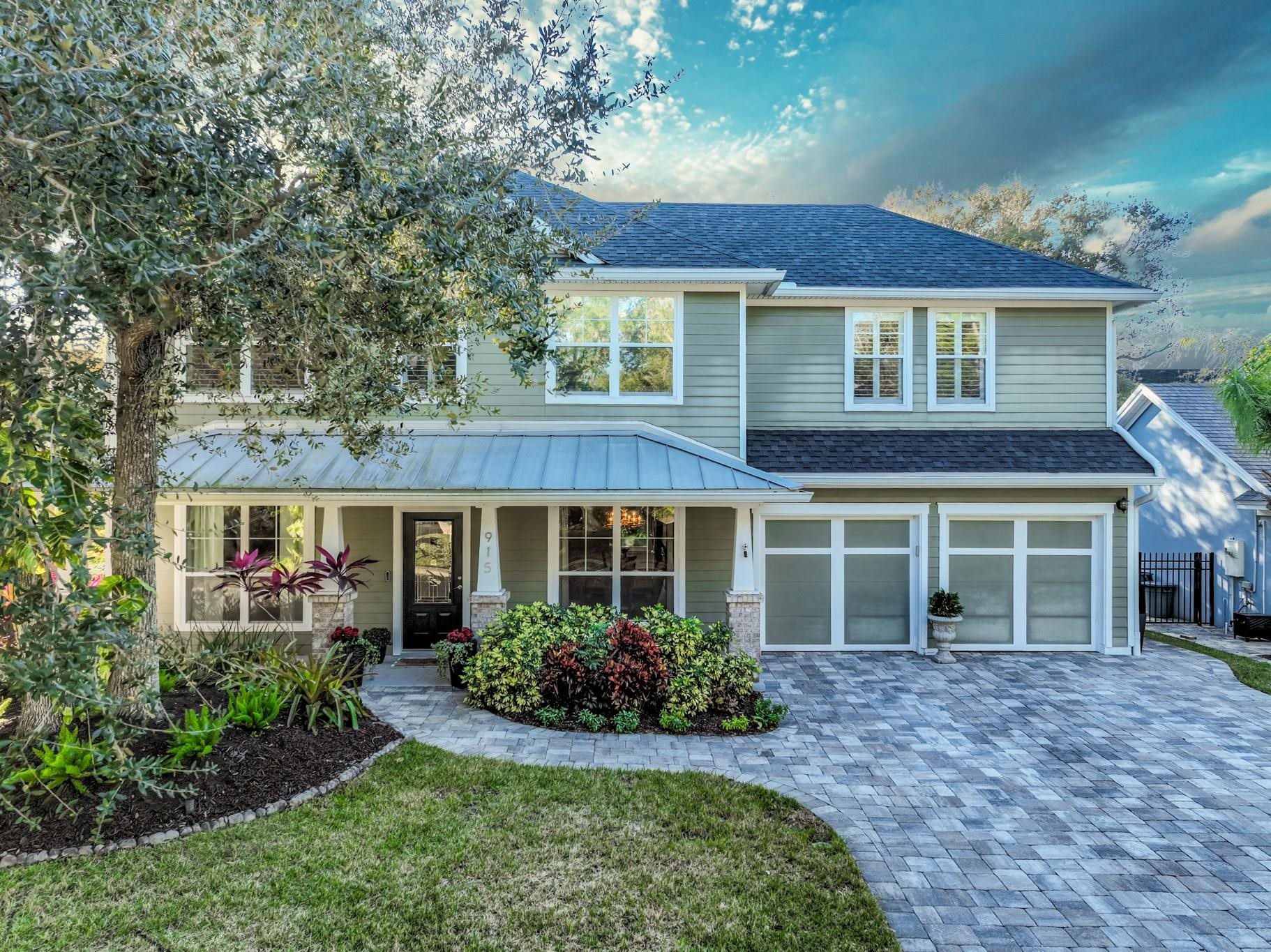 View of front of home with covered porch, a garage, decorative driveway, and a shingled roof