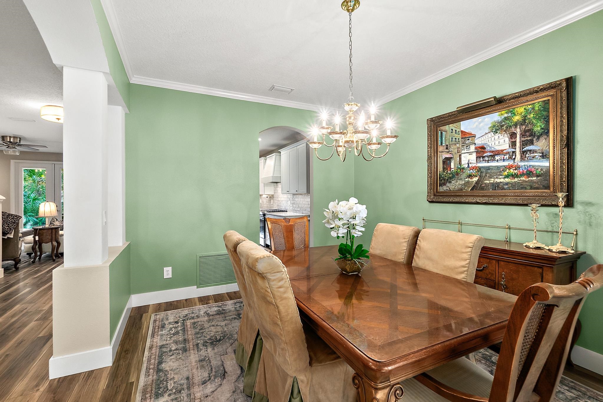 915 Saltwater Circle St. Augustine, FL 32080 - Photo 16 of 60 Dining area with dark wood finished floors, crown molding, arched walkways, and a chandelier