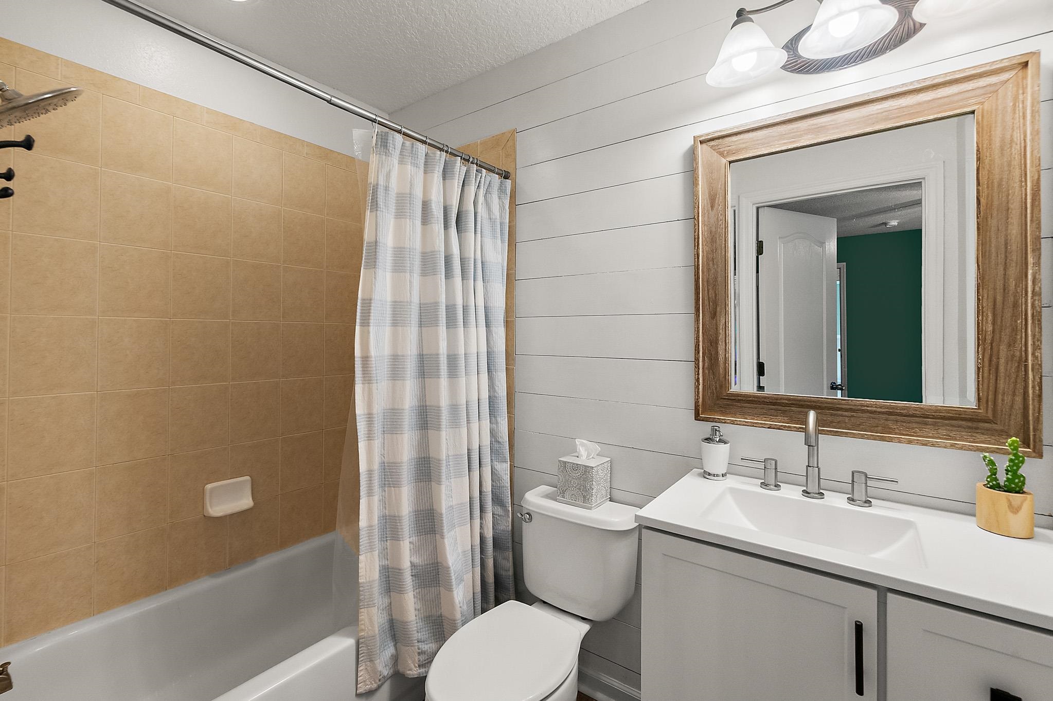 915 Saltwater Circle St. Augustine, FL 32080 - Photo 32 of 60 Bathroom featuring a textured ceiling, shower / bath combo, vanity, and wooden walls