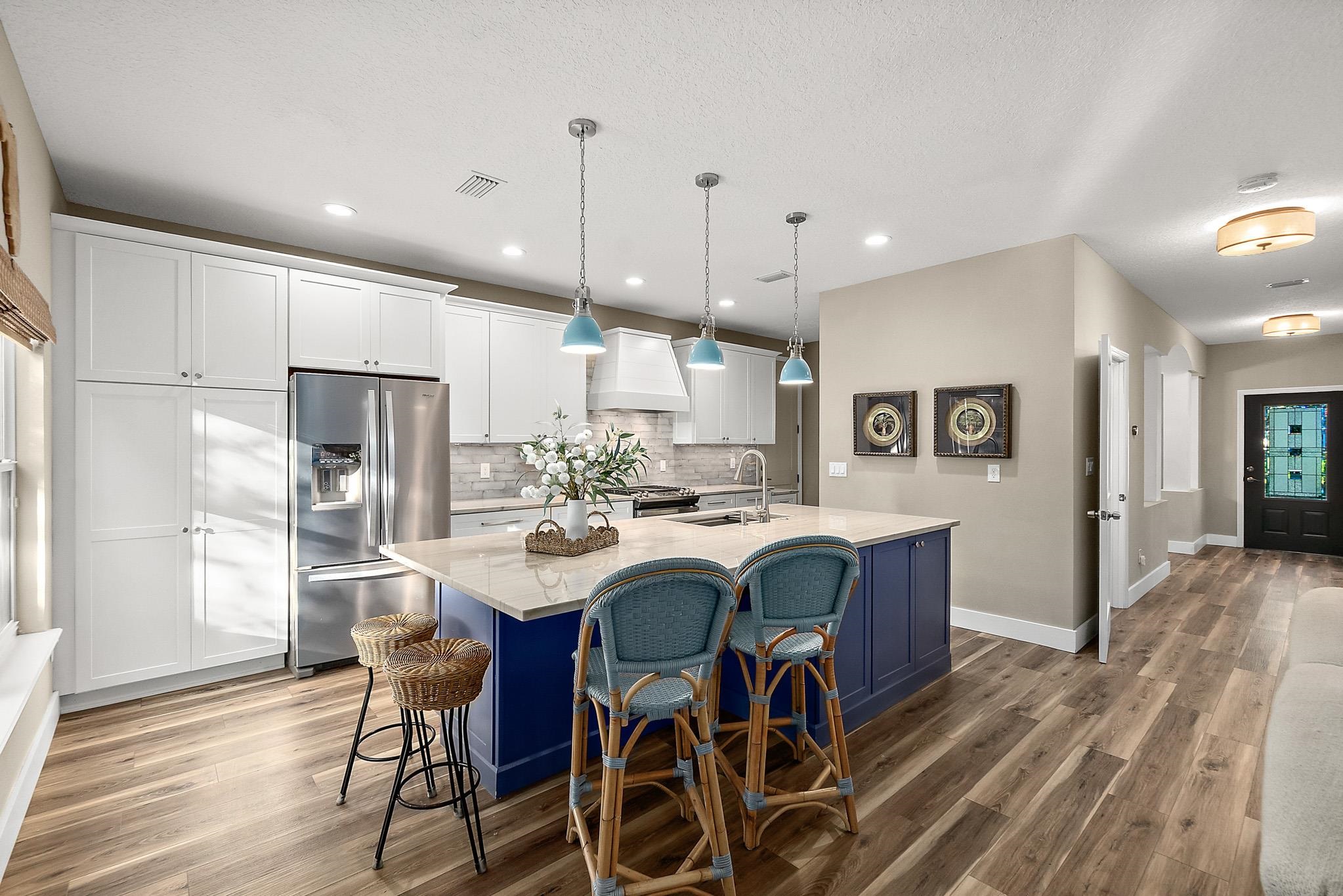 915 Saltwater Circle St. Augustine, FL 32080 - Photo 6 of 60 a kitchen with stainless steel appliances kitchen island granite countertop a refrigerator a stove a microwave oven a dining table and chairs with wooden floor