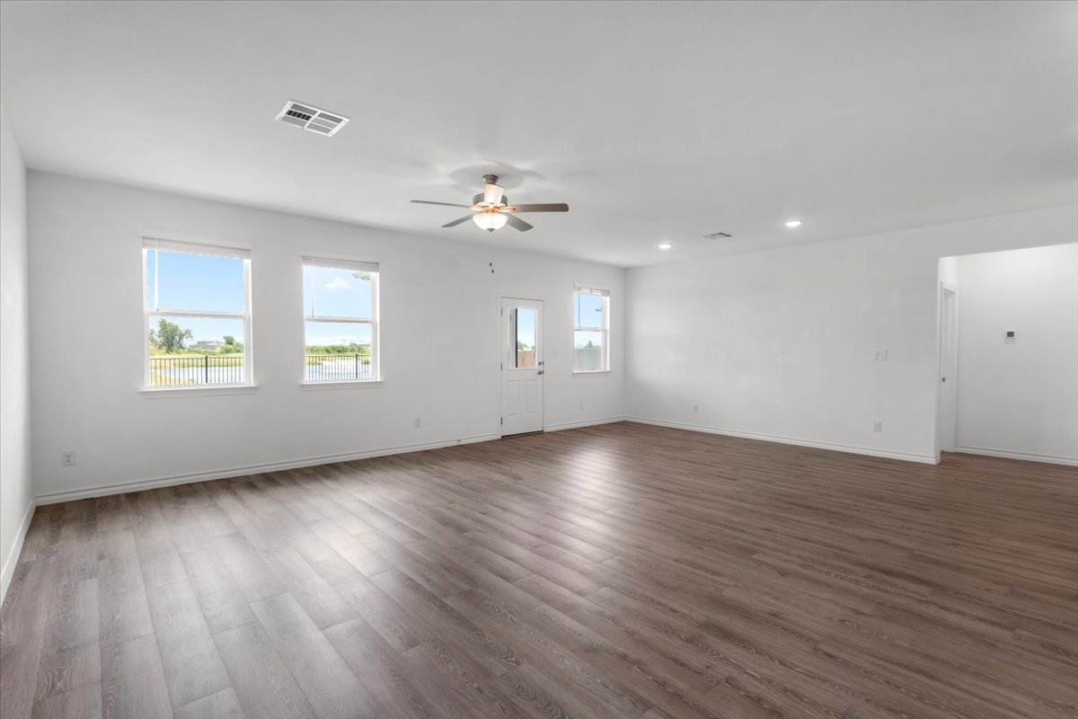 500 Stinchcomb Road Hutto, TX 78634 - Photo 11 of 37 A spacious, naturally illuminated room featuring warm wood flooring and tranquil views of the water.